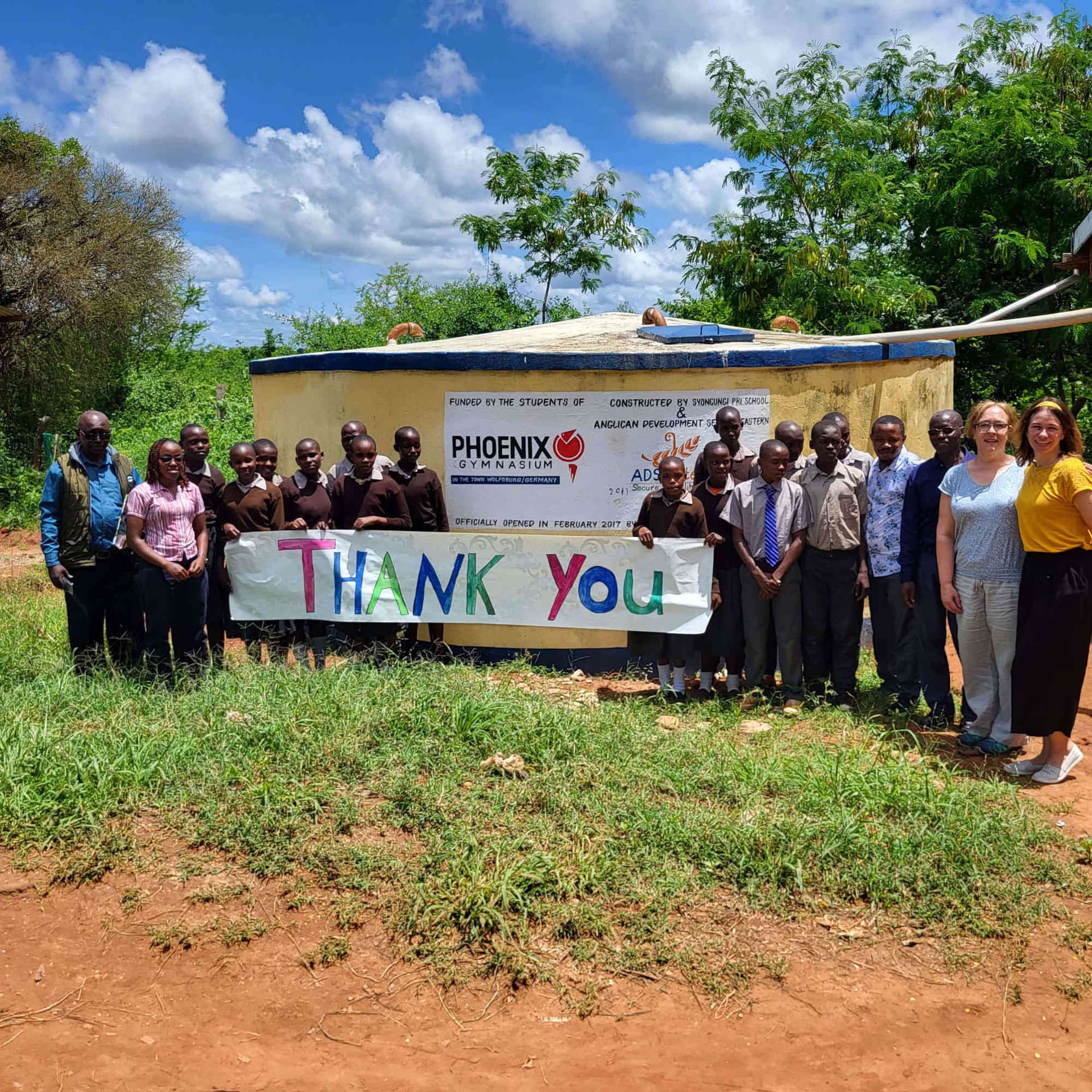 Schülerinnen und Schüler mit Thank-You-Banner bei der Übergabe des Wassertanks in Syongungi